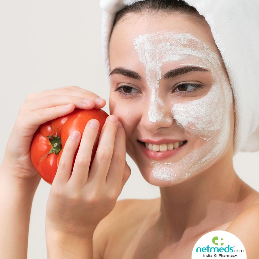 Woman with cream on her face and holding a tomato 